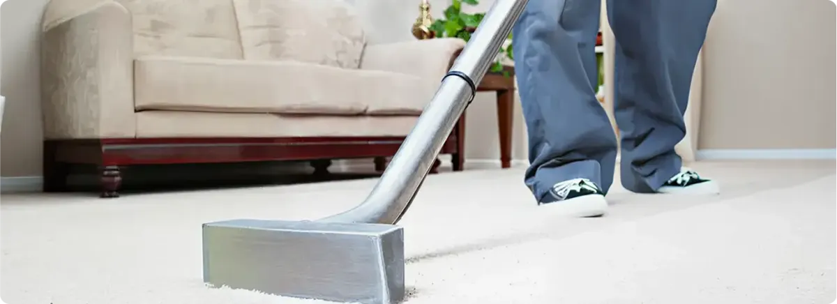 Carpet cleaning technician using a hot-water extraction wand on a light-colored carpet in a living room, Fort Wayne, IN.
